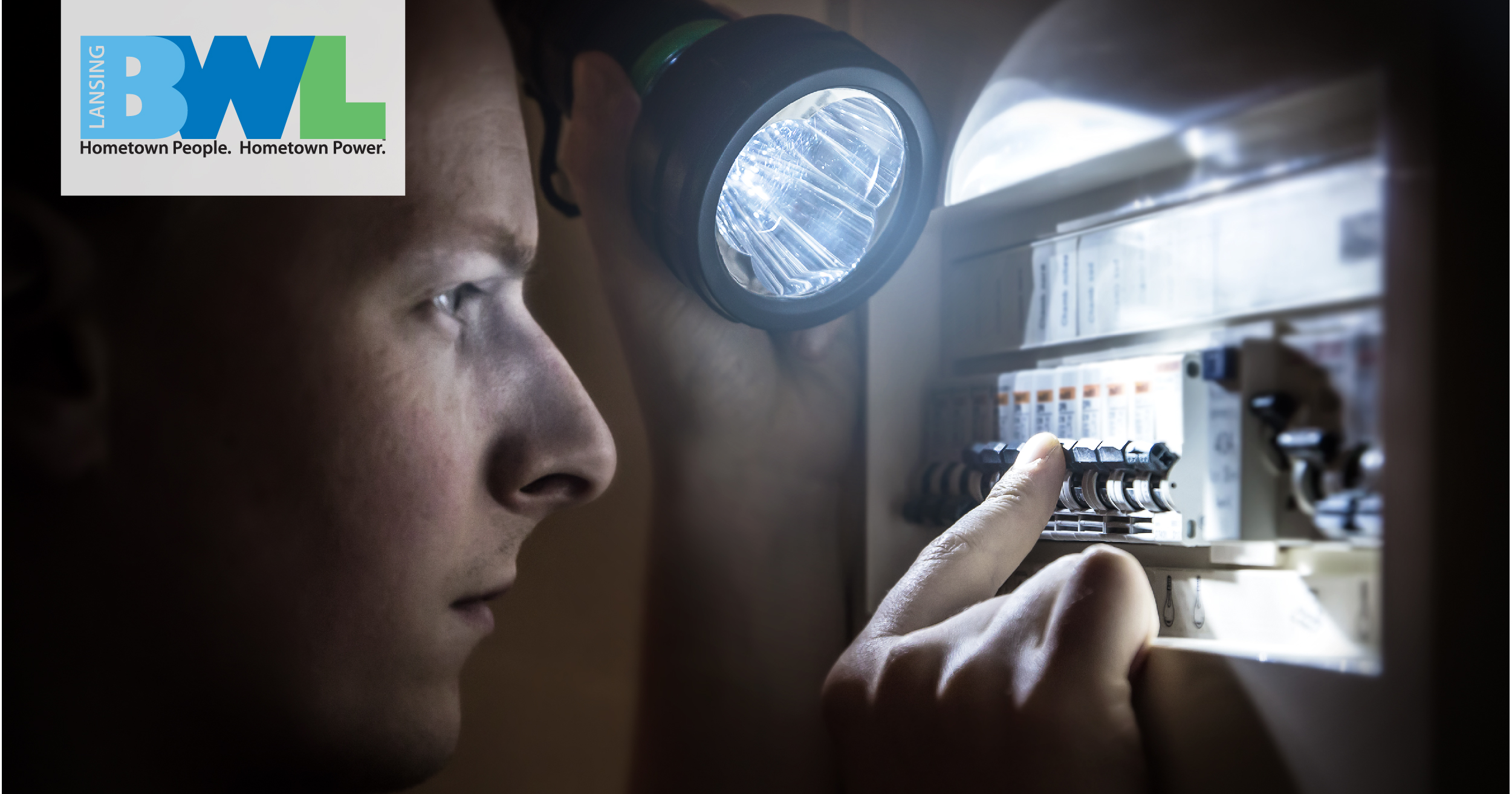 a man with a flashlight looking at an electrical breaker box