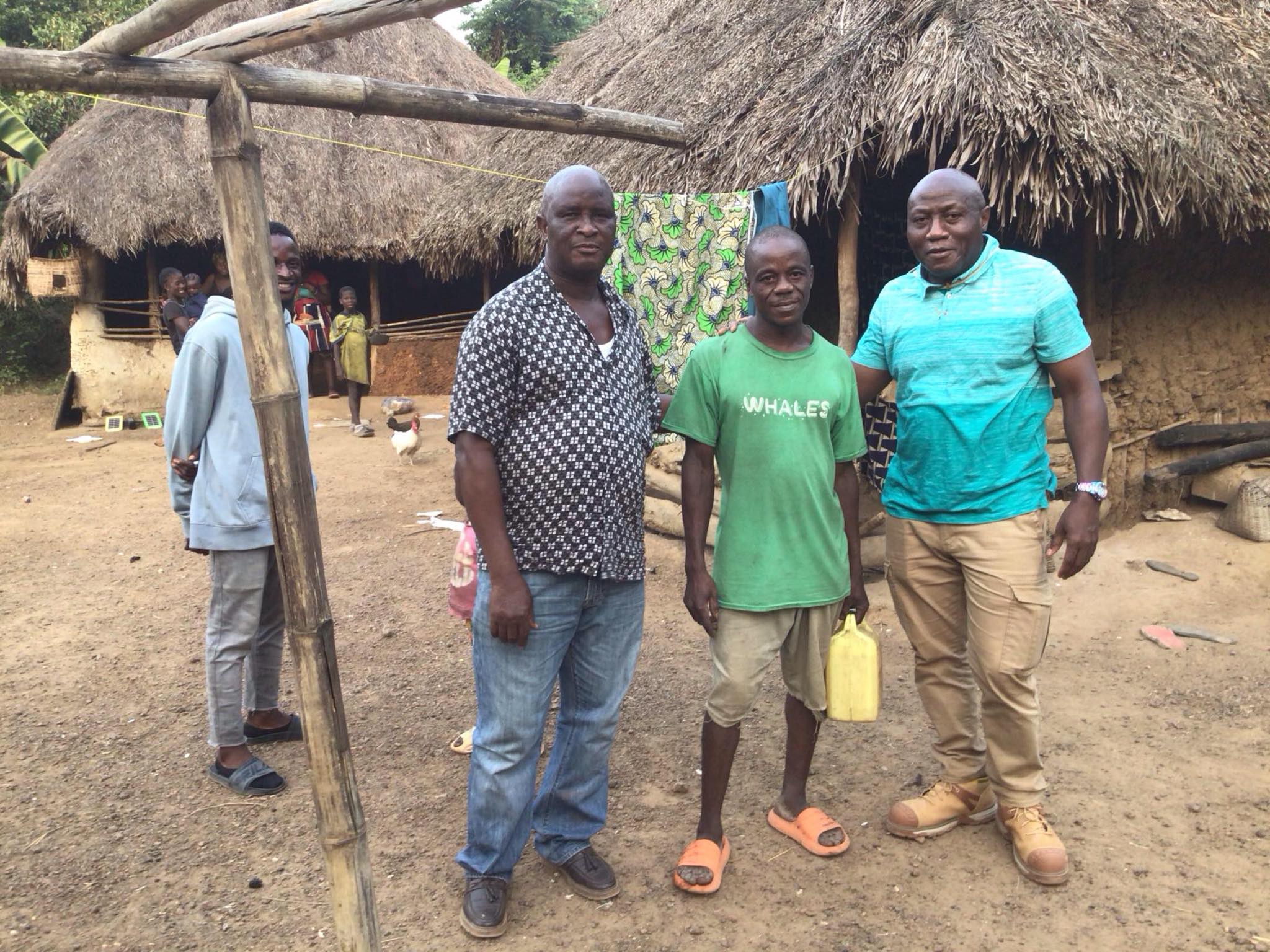 4 men in front of a clothes line and a hut
