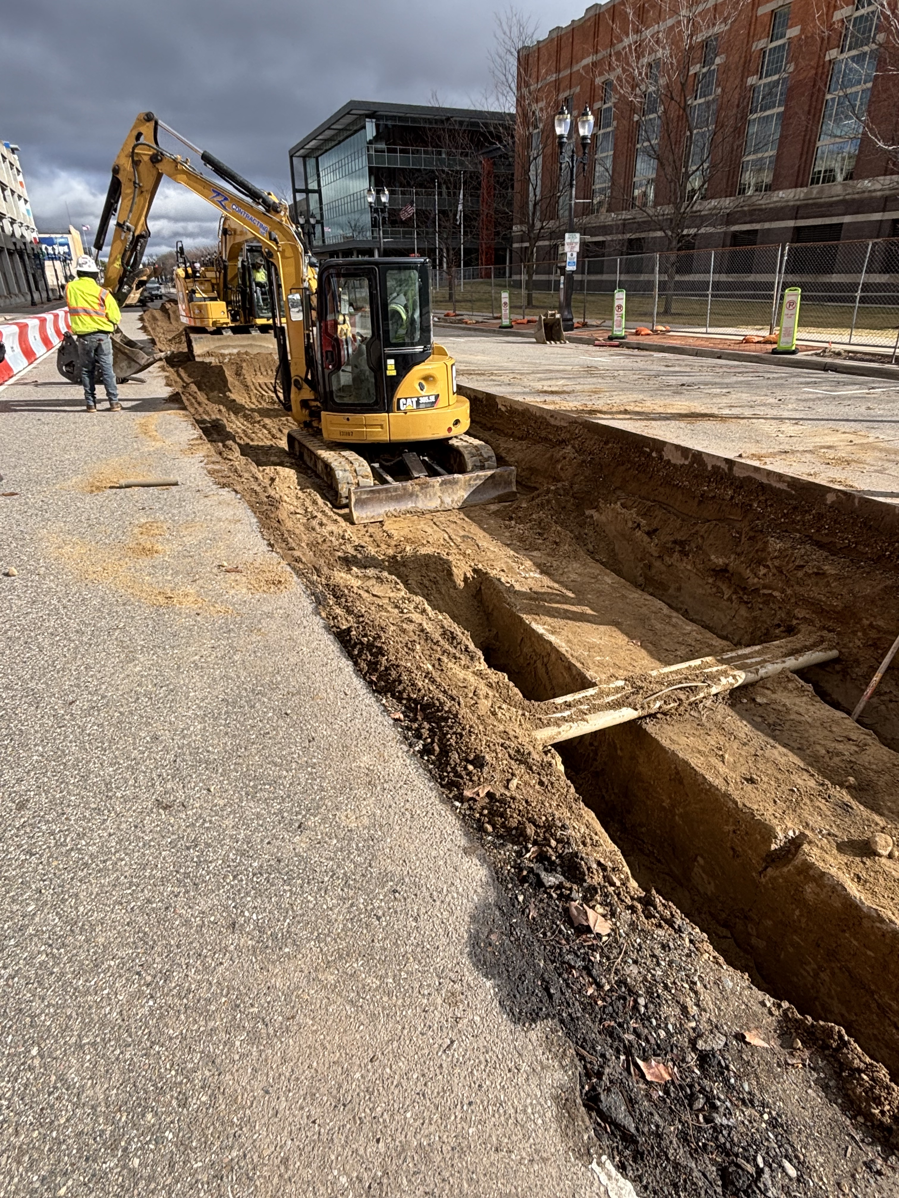 Big hole in the road with a backhoe at the far end, to get to utilities underground 