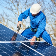 A worker installing solar panels on a roof.